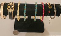 Display of eight signed Stella & Dot bracelets and bangles on a black bracelet stand showing variety of designs and colors