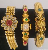Photo of three gold tone enamel bangles and bracelet, showing front view and arrangement of stones and enamel work