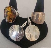 Three piece jewelry lot: amber ring, hammered silver ring, and round silver cufflinks with leaf pattern