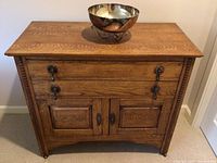 Front view of oak cabinet with silver-plated bowl on top