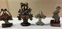 Four cast iron door stops: three floral baskets and one girl with kitten figurine