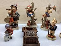 Six main porcelain figurines and wooden inkwell stand on tabletop