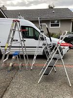 Wide view showing all four items: aluminum ladder, short ladder, SocTone folding step stool, and 3-step Stapleton stool