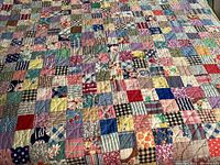 Full view of one multicolored patchwork quilt showing overall condition and fabric pattern.
