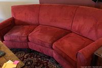 Full view of red curved Ultraleather sofa with visible wear spots