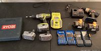 Full lot overview showing two cordless drills, multiple batteries, two chargers, and three sets of drill bits.