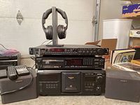 Stack of audio components: Carver CT-6 tuner on top, Sony up-converter CD player in middle, Sony MegaStorage 400 CD changer bottom, speakers at sides, headphones on stand above.
