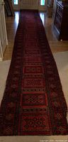 Full length view of red geometric patterned runner on hardwood floor
