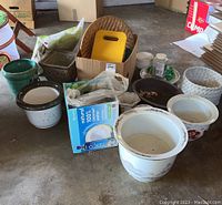 Overview showing group of ceramic pots, woven basket, yellow kneeling pad, and gardening supplies in a box