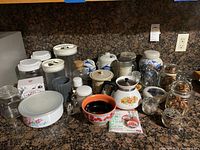 Overview photo showing a collection of kitchenware items including ceramic canisters, glass jars, covered dish, coffee pot, and a small ceramic bowl on a kitchen counter.