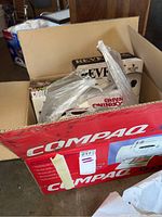 Open cardboard box containing multiple unopened cookware boxes including Revere, CorningWare, CookRight, and TFal, with some plastic bags.