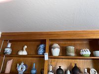Top shelf row of seven assorted porcelain vases and figurines