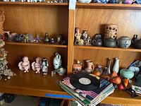Wide view of shelf with ceramic vases, figurines of children, assorted small decorative items, and stack of vinyl albums with one vinyl on top.