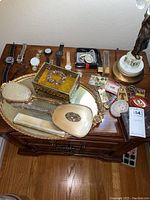 Overall view of lot on wooden dresser showing watches, jewelry box, vanity set and assorted jewelry