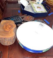 Photo showing marble trivets arranged in a row, ceramic bowl with painted rim, and wooden tray/log piece