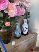 Overview of several vases including two porcelain ones with Asian designs and calligraphy, and a green vase with floral decoration.