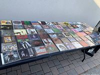 Table with over 150 CDs arranged in rows, mostly 90s-2000s alternative rock albums, visible jewel cases, colorful cover art