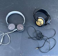 Photo showing both Sony MDR ZX660 headphones (gray and black) and AKG K141 Monitor headphones (black and gold) with cables on black surface.