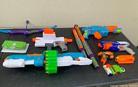 Overview of all Nerf toys and accessories showing blasters in various colors and sizes, laid out on a black surface