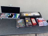 Wide view of poker chips in metal case, card games, beer pong cups and balls, and Gamecraft badminton/volleyball set.