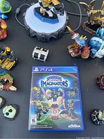 Photo showing Skylanders Imaginators PS4 game case and disc among various character figurines and portal base