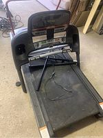 Full view of Tempo Fitness treadmill showing control console, running belt, hydraulic lift over the belt, and dust on surface.
