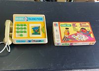 Photo of Big Bird Talking Phone and boxed Sesame Street Quiz Game on black surface
