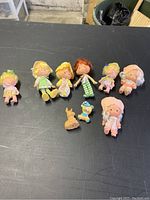 Full view of 8 Strawberry Shortcake dolls and character figurines laid out on black surface
