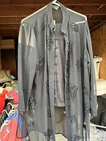 Sheer gray jacket with floral embroidery hanging on white hanger.