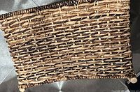 Close-up image showing the woven texture and natural fiber materials of the basket along with its wooden supports.