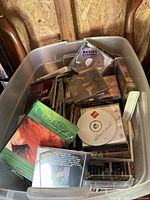 Plastic bin filled with assorted CDs, some titles visible including blues and Celtic music