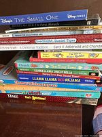 Stack of children's books with titles visible including Disney Press, Peter Rabbit, Thomas & Friends, and math books