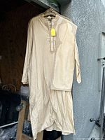 Beige traditional suit set consisting of a kurta with embellishments on neckline and cuffs, paired with matching fabric piece.