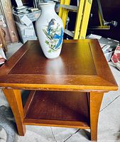 Wooden end table with square top and decorative bird porcelain vase on top