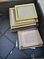 Top view of a stack of assorted picture frames showing varied sizes and gold, silver, and wooden finishes.