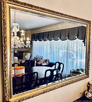 Mirror hanging on wall reflecting dining room and chandelier