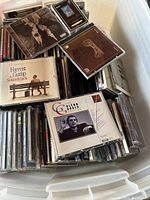 Large plastic box filled with assorted CDs and DVDs, some titles visible such as Forrest Gump Soundtrack and Glenn Gould music.