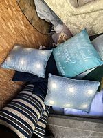 Various mixed throw pillows piled together showing different patterns and text