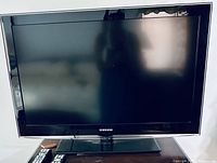 Front view of Samsung 37-inch TV on stand with two remotes visible below.