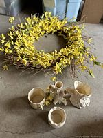 Close-up photo of yellow artificial flower wreath and four Royal Doulton ceramic pieces on floor