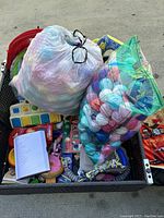 Bag filled with various toys and craft material including plush toys, yarn balls, books, and small items.