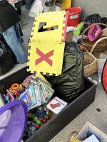 Photo showing alphabet interlocking foam floor panels with letters X and Y visible, pile of children's books and toys including Lego blocks and wooden toys in a basket.
