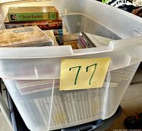 Photo showing the plastic storage container with a variety of media items inside including VHS tapes, CDs and books.