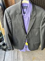 Men's gray blazer over purple dress shirt on a hanger.