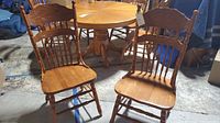 Two wooden dining chairs front view showing spindle backs and contoured wooden seats.
