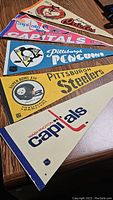 Image showing all five sports banners laid out on a table: Baltimore Orioles, two Washington Capitals, Pittsburgh Penguins, and Pittsburgh Steelers.