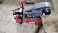 Side view of Craftsman air compressor showing 1.5 HP, 2 GAL capacity, and 125 PSI max pressure label.