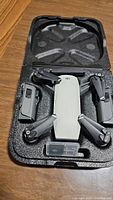 Folded DJI Spark drone and one battery seated in black foam-lined case