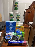 Full view of lot showing Bounty paper towels, Kleenex tissue boxes, Swiffer Dusters, Ziploc bags, duct tape rolls, Reynolds Wrap aluminum foil, timer, twin string, and wipes