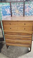 Front view of wooden mid-century dresser with five drawers, two top small drawers with round knobs and three lower large drawers with linear pulls.